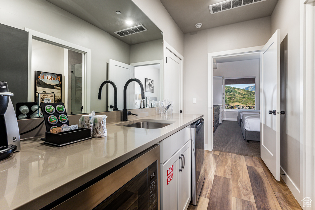 Kitchen with white cabinets, light wood-type flooring, dishwashing machine, and sink