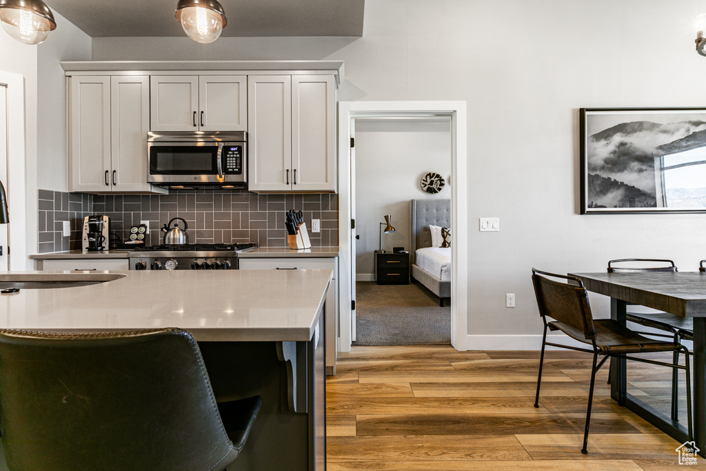 Kitchen with tasteful backsplash, light carpet, sink, white cabinets, and stove