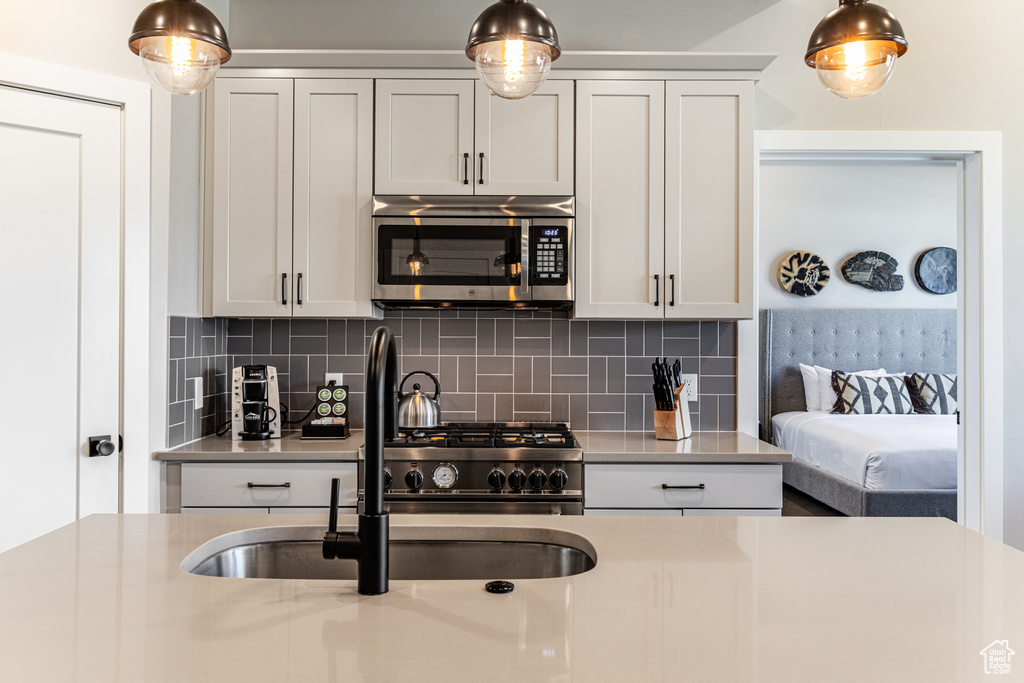 Kitchen featuring appliances with stainless steel finishes, sink, tasteful backsplash, and hanging light fixtures