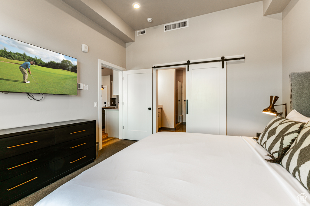 Bedroom featuring ensuite bath, a barn door, and dark hardwood / wood-style flooring