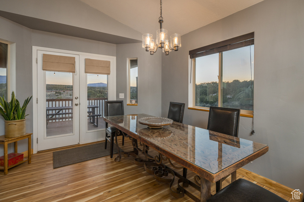 Dining area with a chandelier, lofted ceiling, hardwood / wood-style floors, and a wealth of natural light