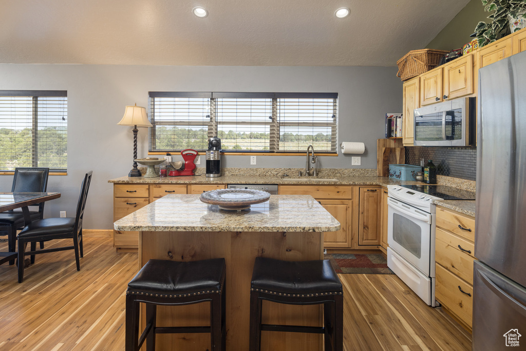 Kitchen with appliances with stainless steel finishes, light wood-type flooring, sink, and a kitchen island