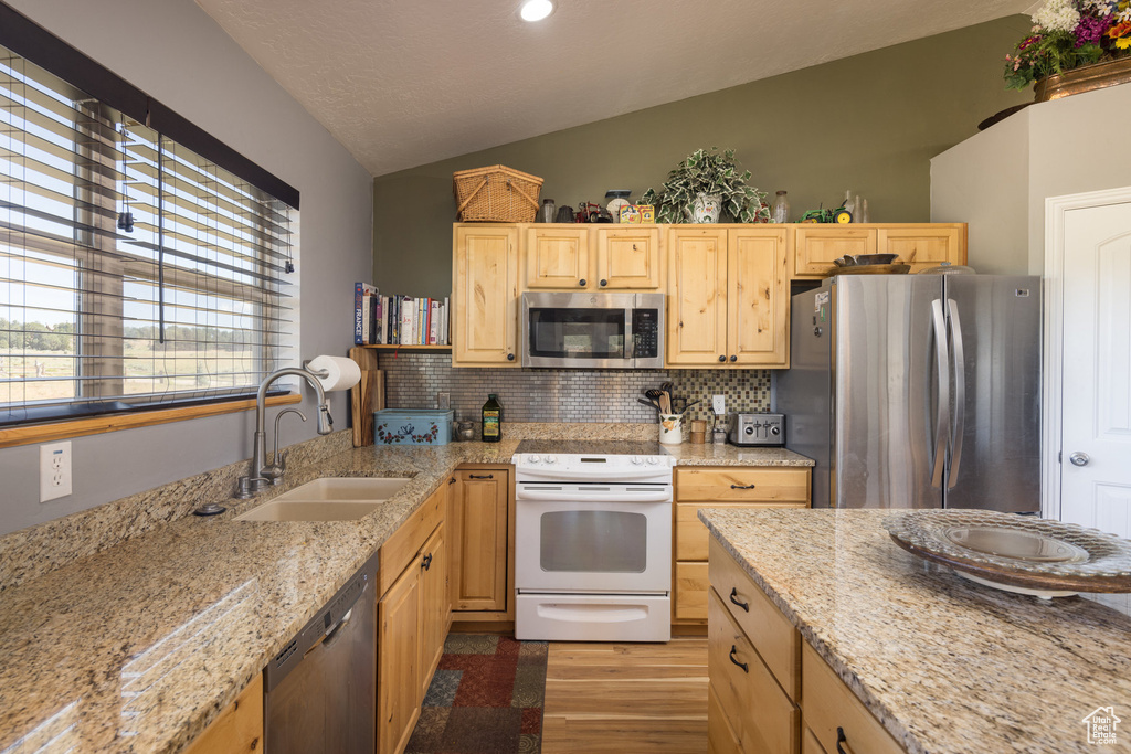 Kitchen featuring tasteful backsplash, stainless steel appliances, light brown cabinets, sink, and lofted ceiling