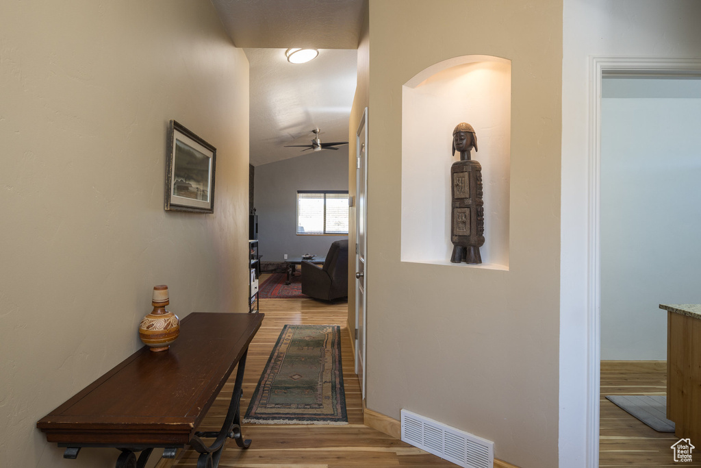 Hallway featuring vaulted ceiling and light hardwood / wood-style flooring