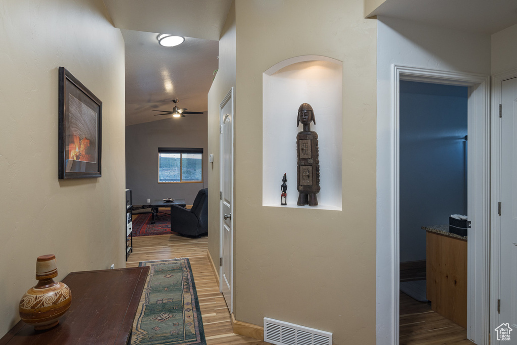 Hall with light hardwood / wood-style floors and vaulted ceiling