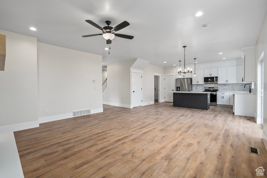 Unfurnished living room featuring light wood-type flooring, sink, and ceiling fan