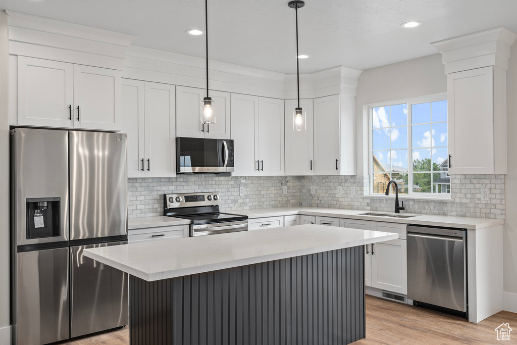 Kitchen featuring light wood-type flooring, stainless steel appliances, sink, and white cabinetry