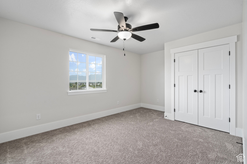 Unfurnished bedroom featuring ceiling fan, light colored carpet, and a closet