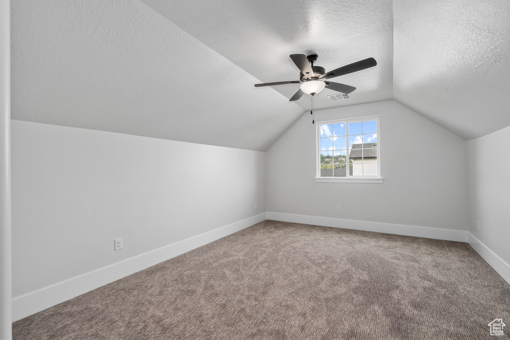 Bonus room with ceiling fan, carpet flooring, a textured ceiling, and vaulted ceiling