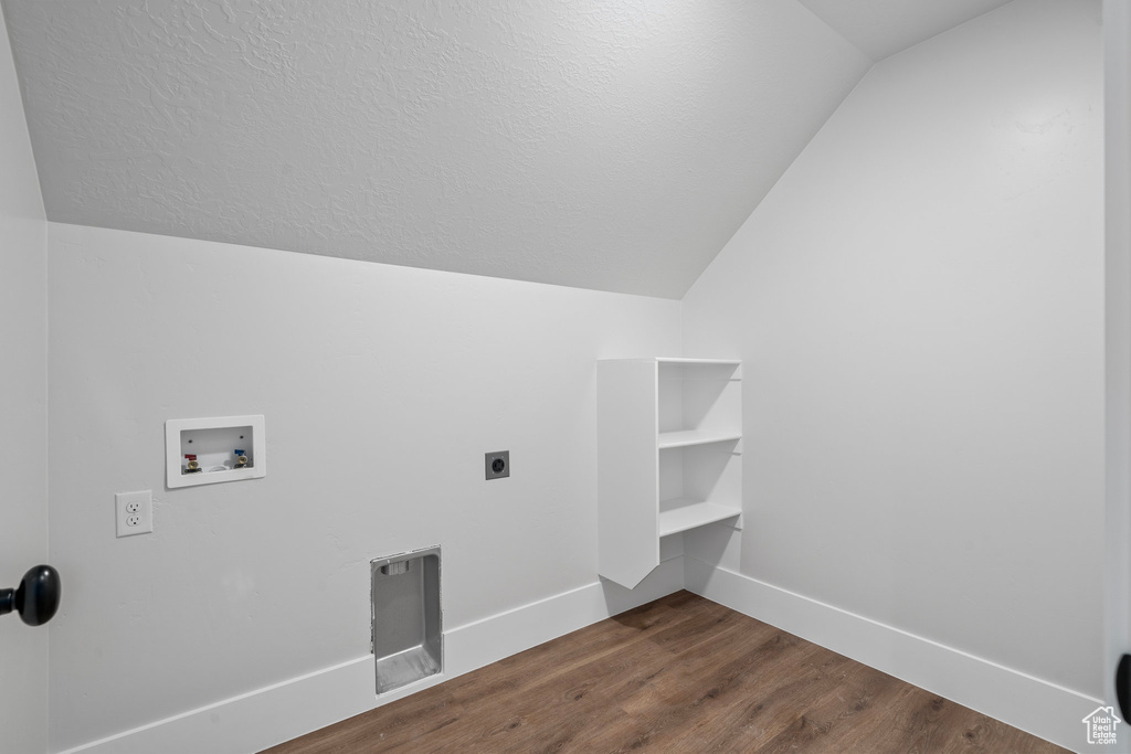 Washroom with electric dryer hookup, hookup for a washing machine, dark hardwood / wood-style flooring, and a textured ceiling