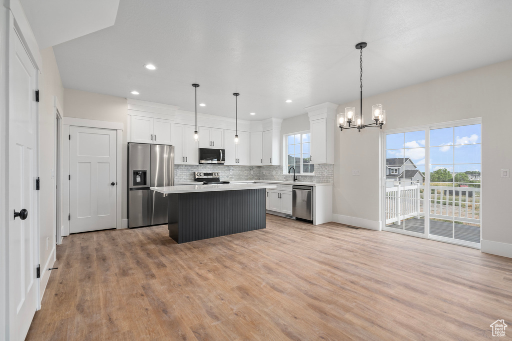 Kitchen featuring appliances with stainless steel finishes, decorative light fixtures, and light hardwood / wood-style floors