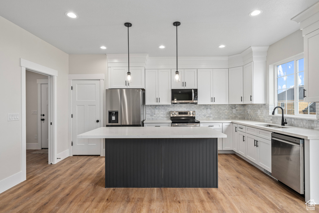 Kitchen with light wood-type flooring, stainless steel appliances, sink, and a kitchen island