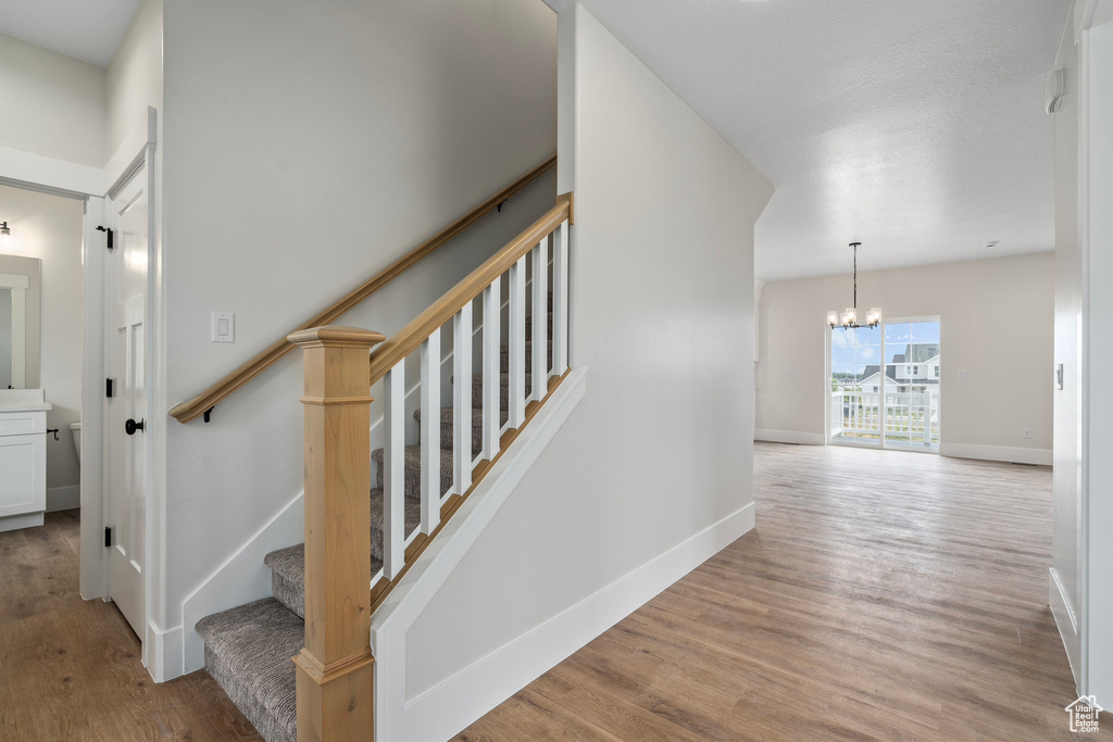 Staircase with wood-type flooring and a chandelier