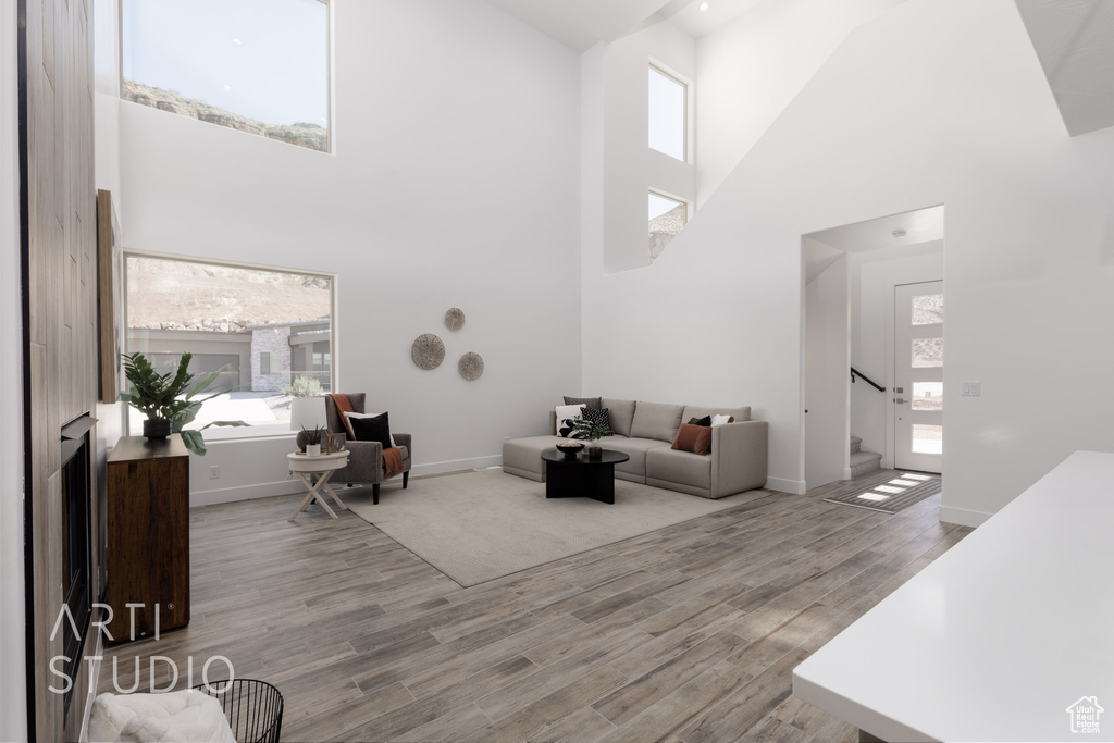 Living room featuring light wood-type flooring and a towering ceiling