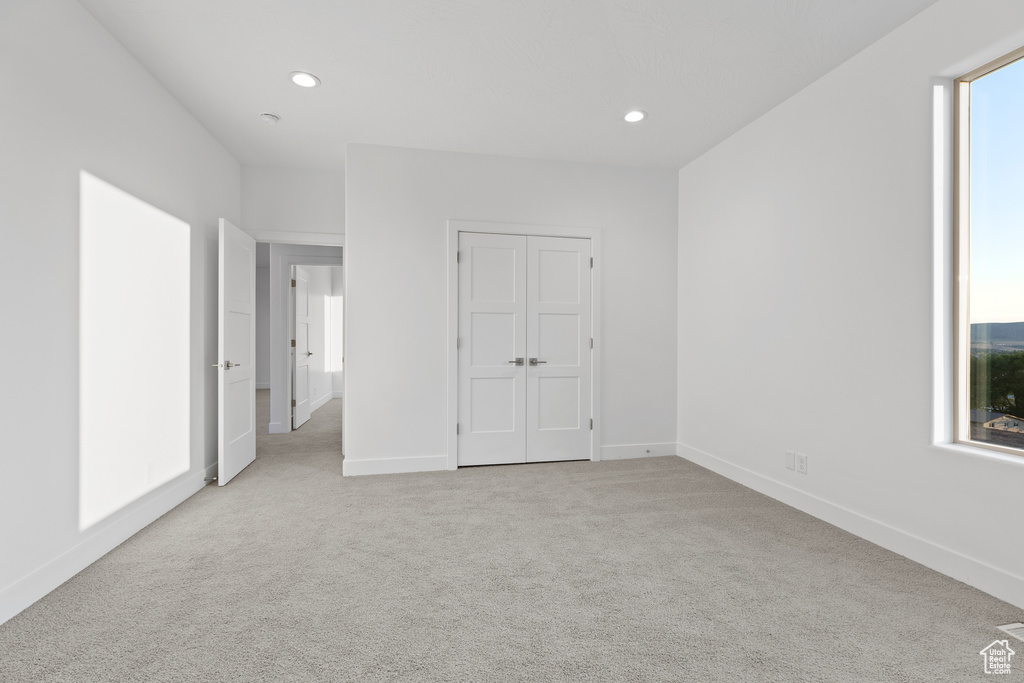 Unfurnished bedroom with light carpet, recessed lighting, and a closet