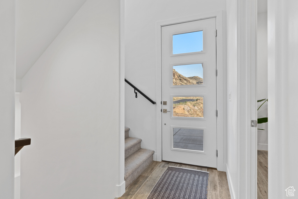 Doorway to outside with light wood finished floors and stairs