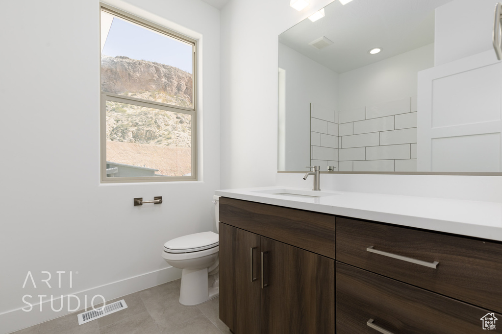 Bathroom featuring a healthy amount of sunlight, vanity, toilet, and tile patterned floors