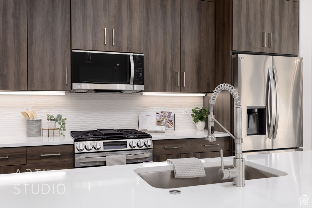 Kitchen featuring dark brown cabinets, stainless steel appliances, sink, and decorative backsplash