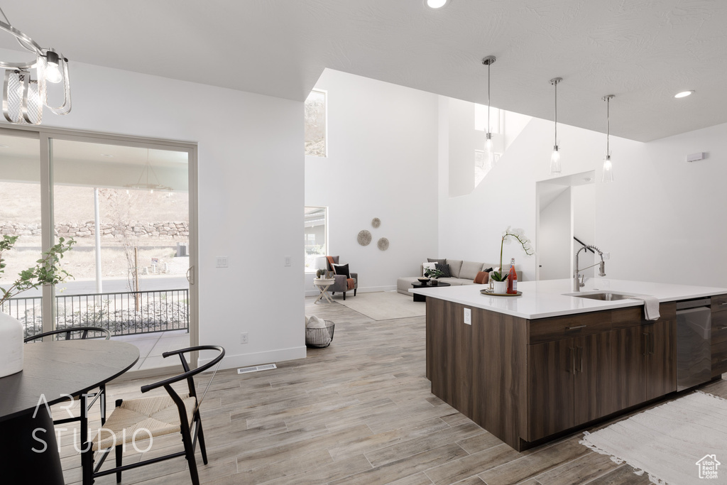 Kitchen with dark brown cabinets, light wood-type flooring, dishwasher, sink, and decorative light fixtures