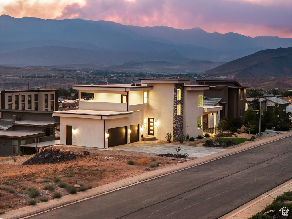 View of front of home featuring a mountain view, stucco siding, a garage, concrete driveway, and stone siding