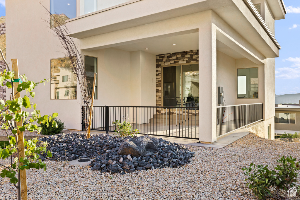 Entrance to property with stucco siding, stone siding, and a patio