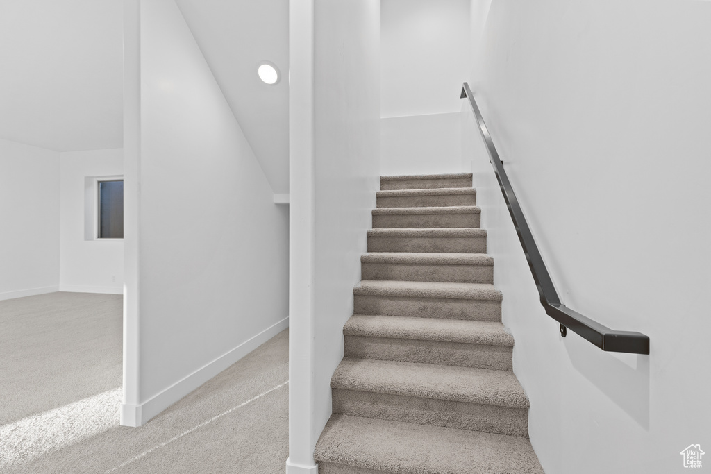 Staircase featuring carpet floors and vaulted ceiling