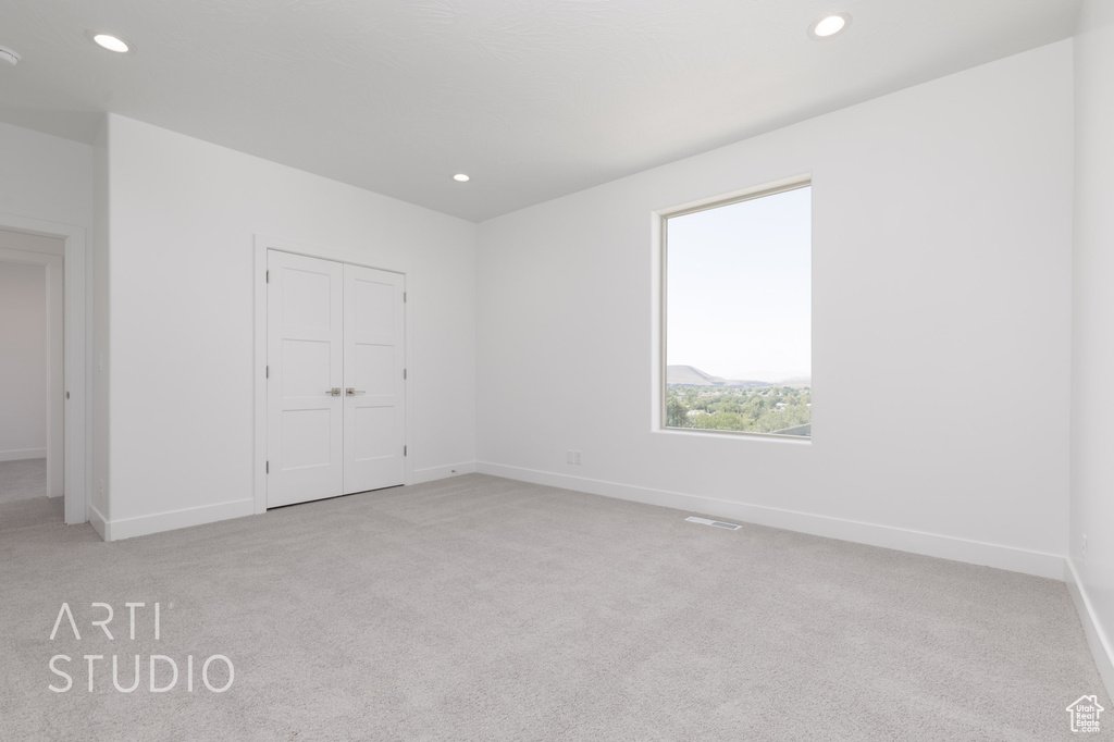 Unfurnished bedroom with light carpet and a closet