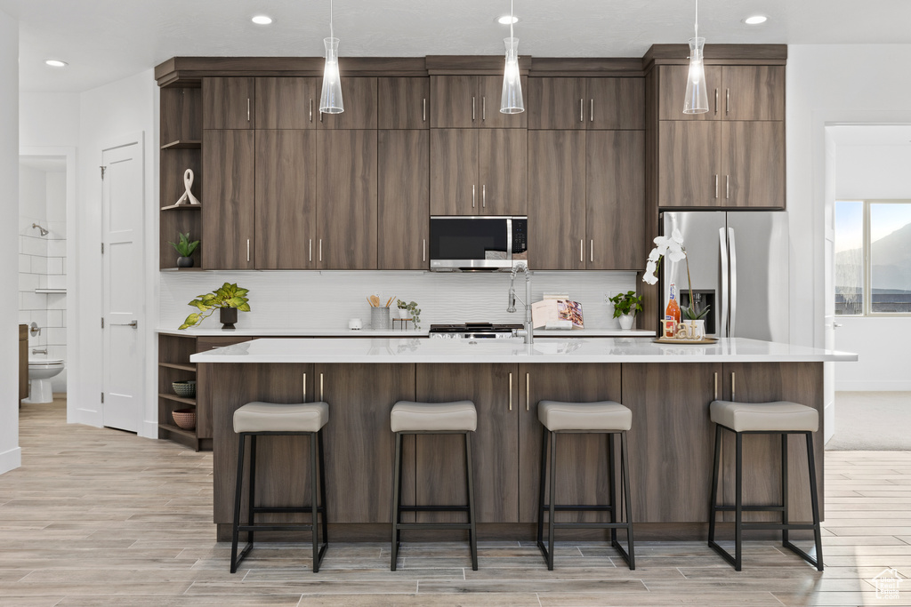 Kitchen featuring open shelves, appliances with stainless steel finishes, light countertops, light wood-style floors, and recessed lighting