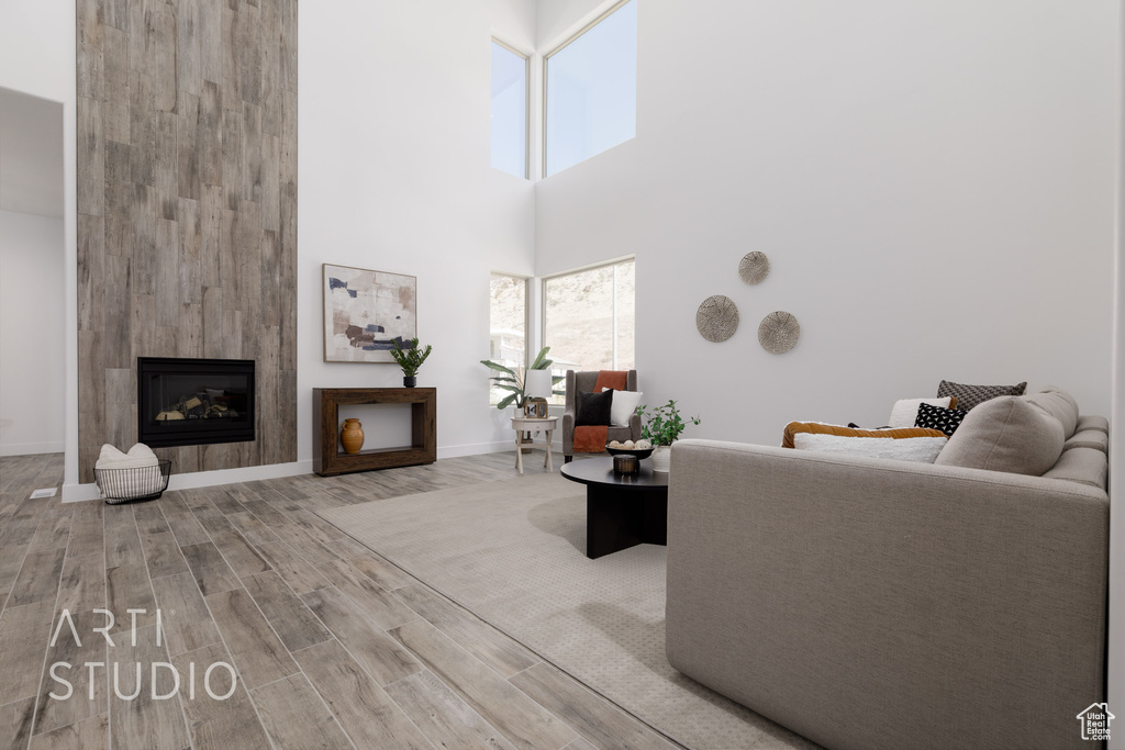 Living room featuring a high ceiling, hardwood / wood-style flooring, and a fireplace