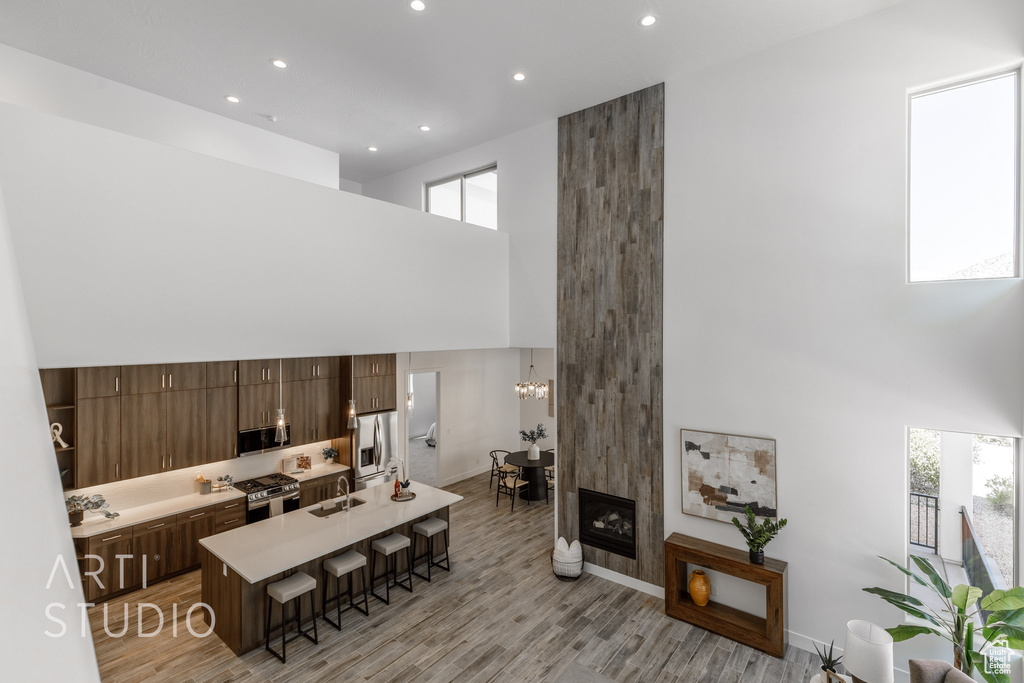 Living room with a towering ceiling, a fireplace, light wood-type flooring, and sink