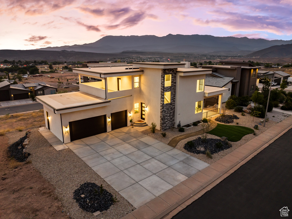 View of front facade featuring stucco siding, a mountain view, a balcony, and stone siding