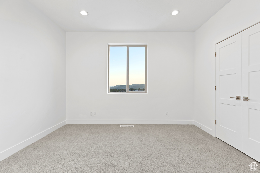 Unfurnished bedroom with light colored carpet, recessed lighting, and a closet
