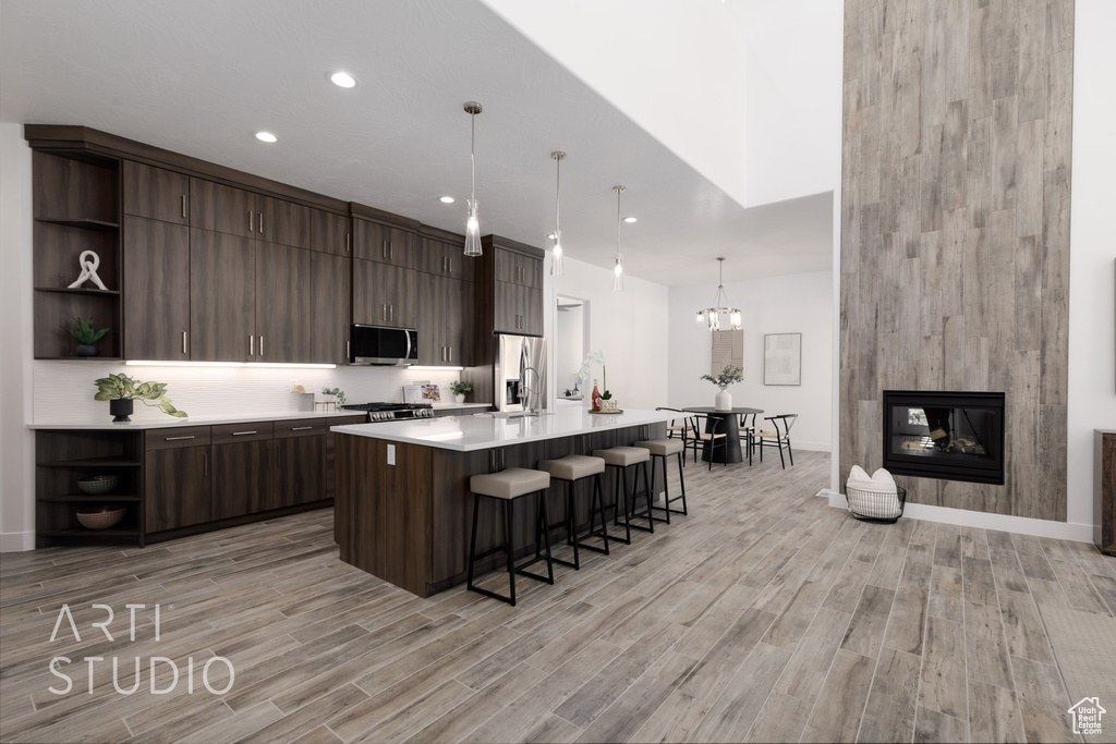 Kitchen with dark brown cabinets, light wood-type flooring, and hanging light fixtures