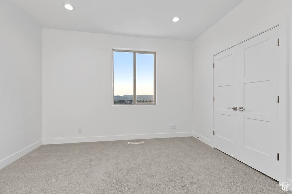 Unfurnished bedroom with light carpet, recessed lighting, and a closet