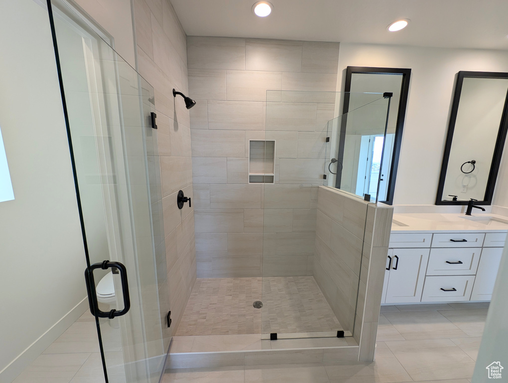 Bathroom featuring tile patterned floors, double vanity, and an enclosed shower