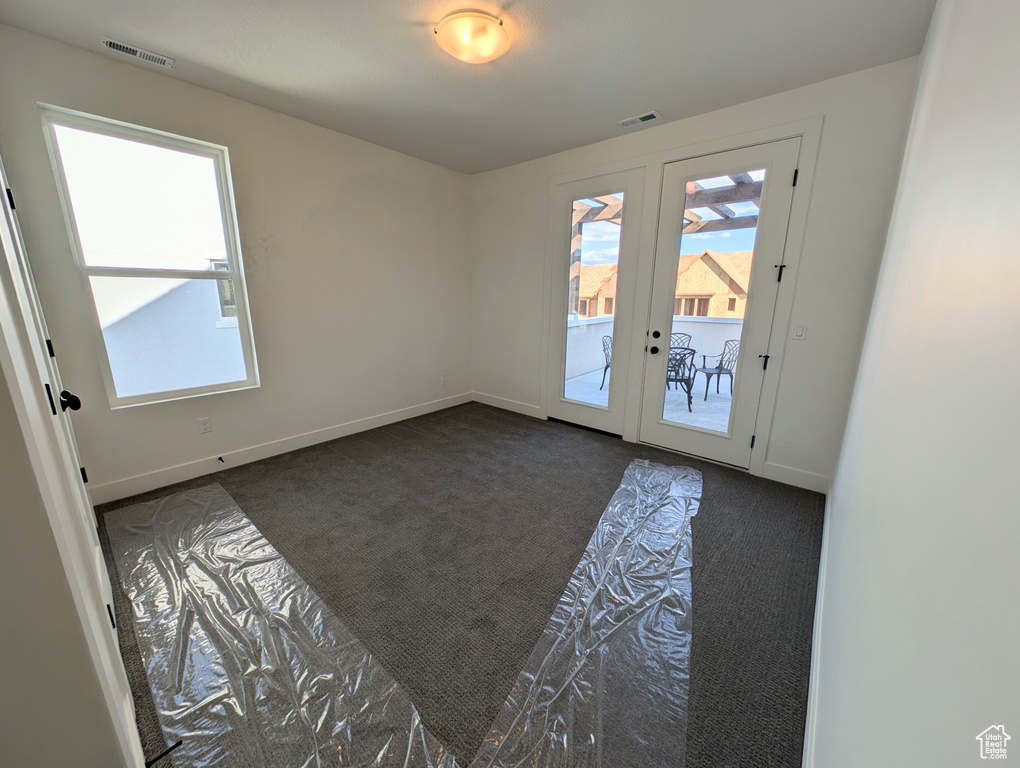 Spare room with dark colored carpet and french doors