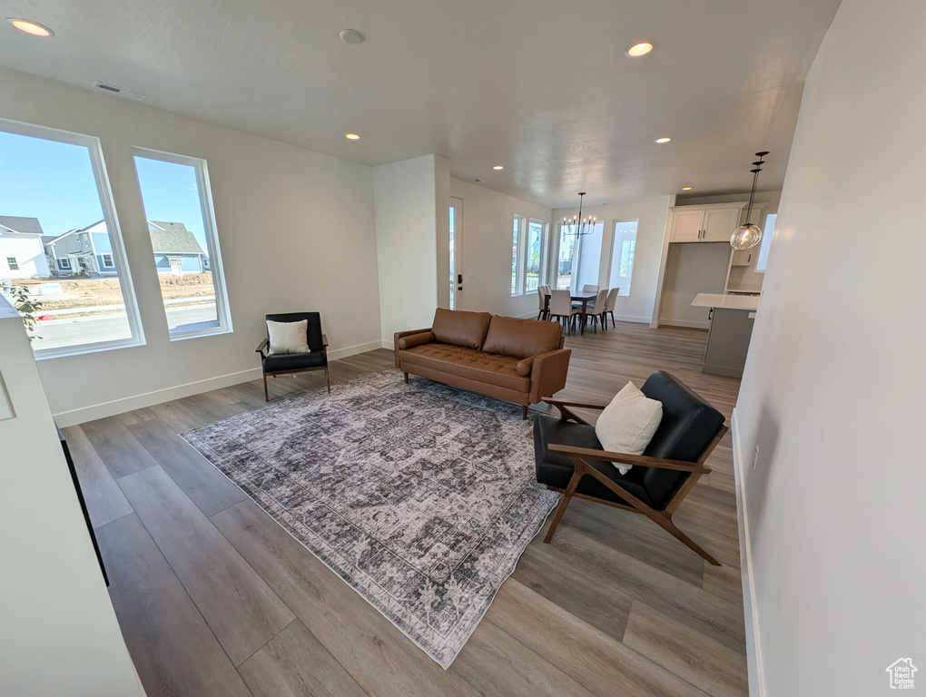 Living room with light hardwood / wood-style flooring, an inviting chandelier, and a healthy amount of sunlight