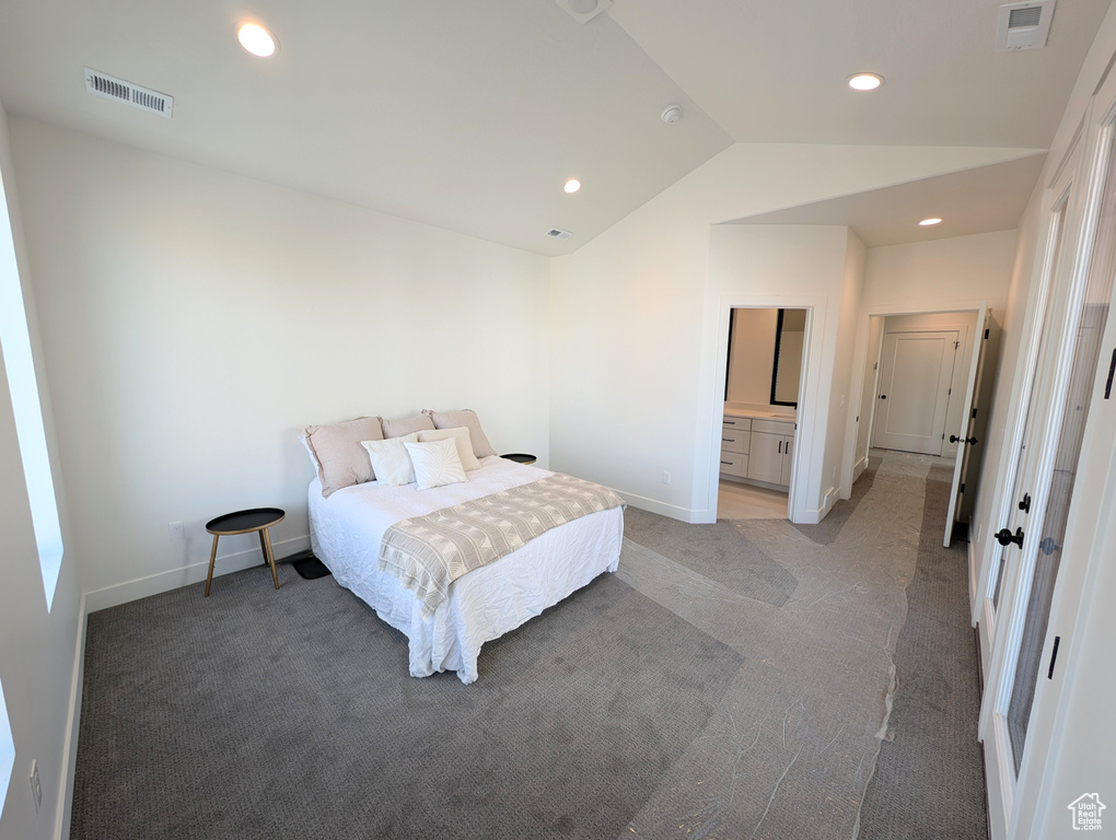 Bedroom featuring light colored carpet, lofted ceiling, and ensuite bathroom