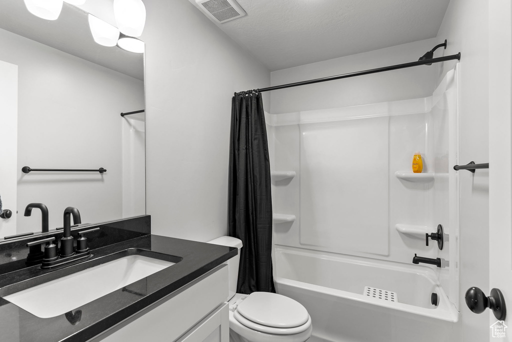 Full bathroom featuring toilet, vanity, and shower / bath combination with curtain