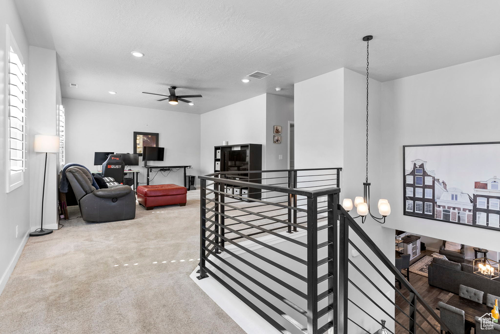 Interior space featuring ceiling fan with notable chandelier and carpet floors