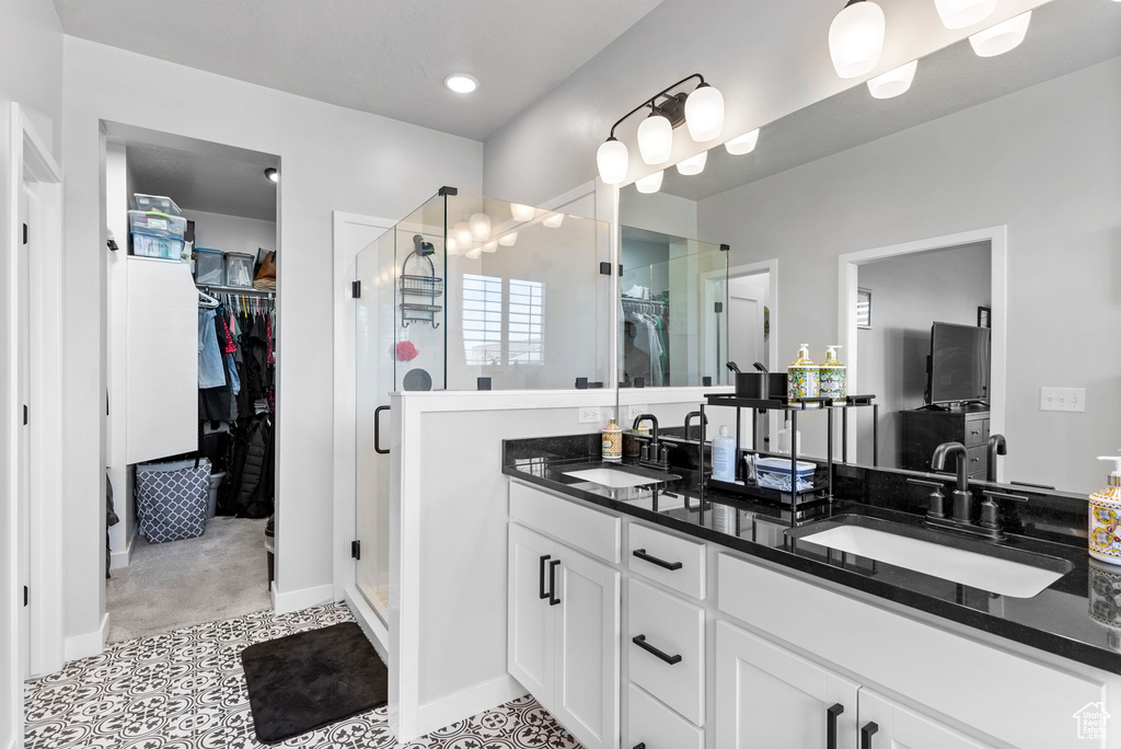 Bathroom with a shower with shower door, tile patterned floors, and double sink vanity