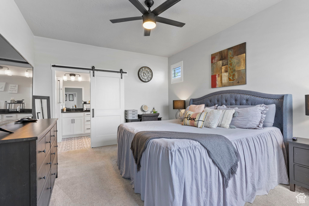 Bedroom featuring ceiling fan, a barn door, connected bathroom, and light tile patterned floors