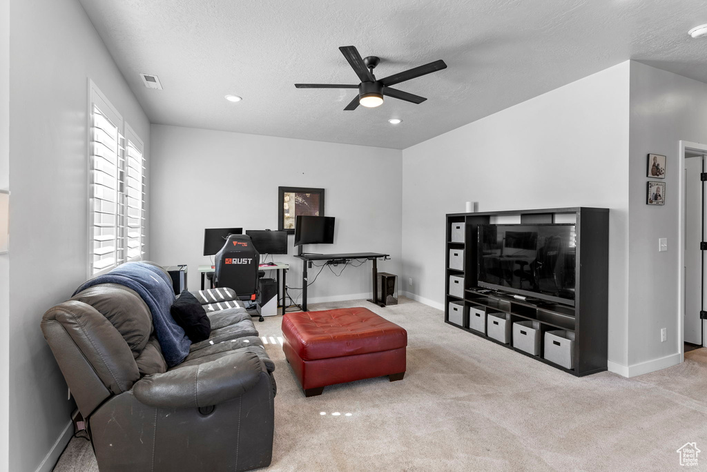 Living room with ceiling fan, a textured ceiling, and light carpet