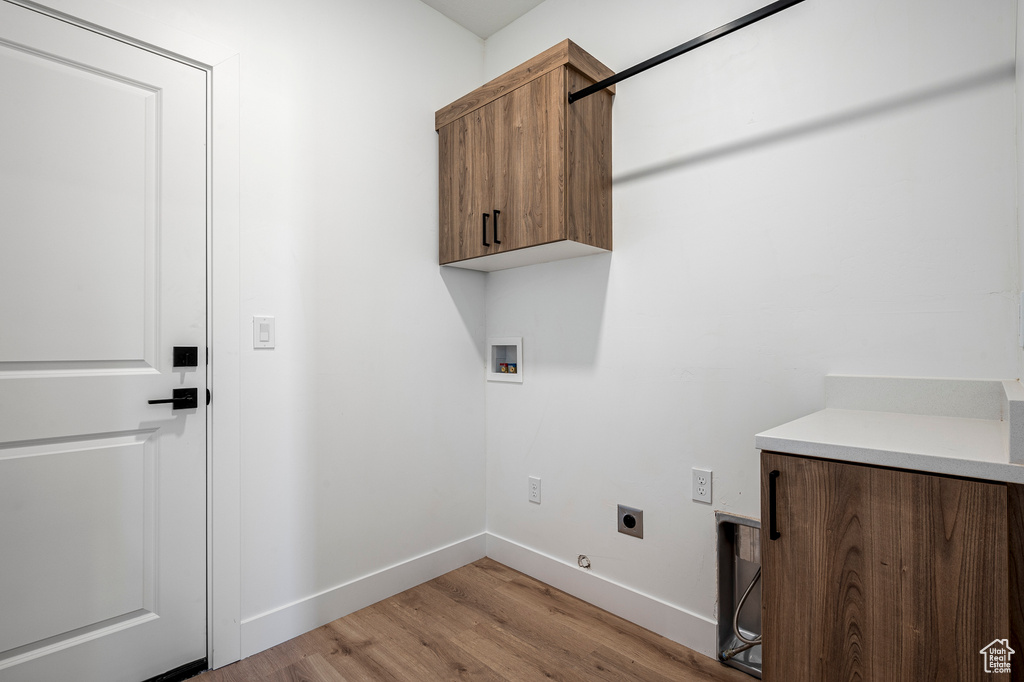 Washroom featuring hookup for an electric dryer, hookup for a washing machine, light hardwood / wood-style floors, and cabinets