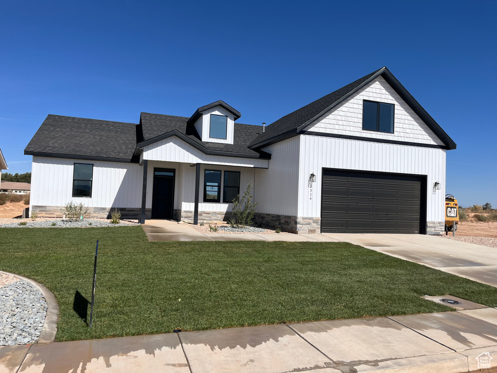 Modern inspired farmhouse with a front yard and a garage