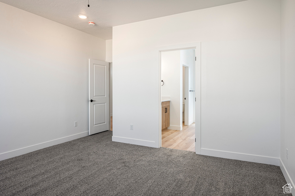 Unfurnished bedroom featuring light carpet and ensuite bathroom