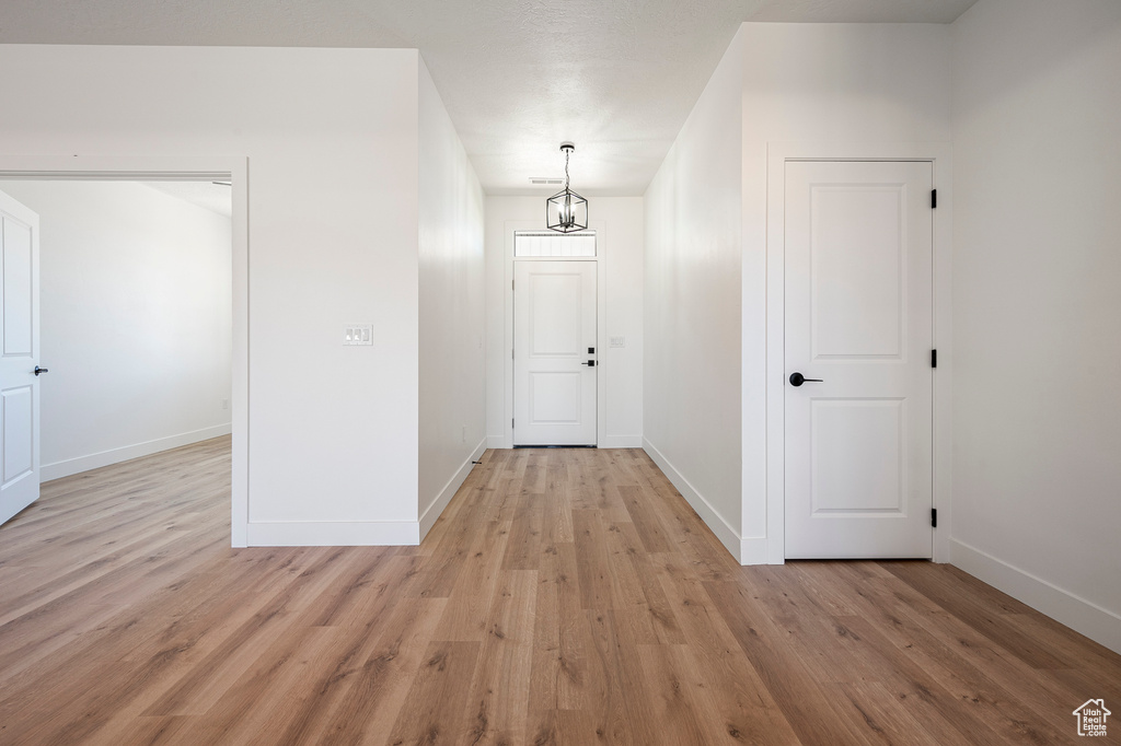 Hallway with light hardwood / wood-style floors and a chandelier