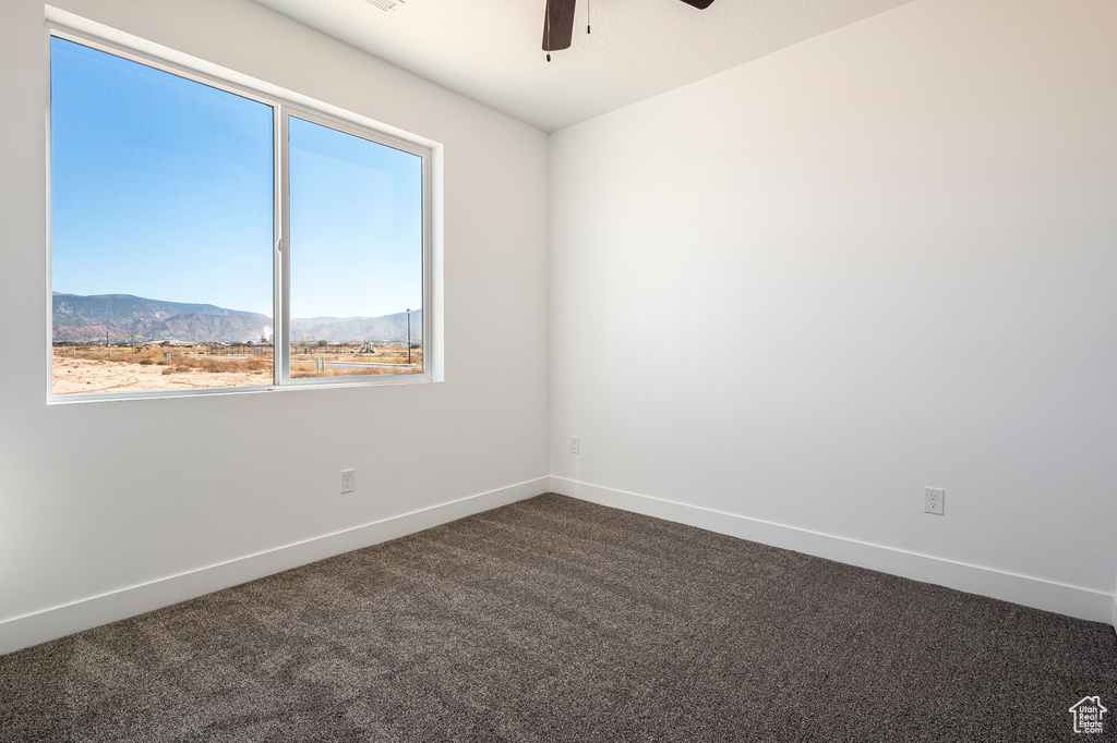 Carpeted empty room featuring a mountain view and ceiling fan