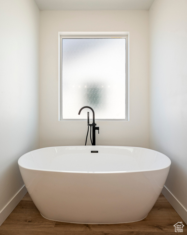 Bathroom featuring a tub to relax in, a healthy amount of sunlight, and wood-type flooring