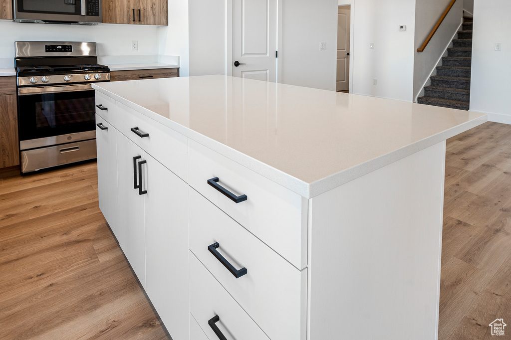 Kitchen featuring a kitchen island, white cabinets, stainless steel appliances, and light hardwood / wood-style floors